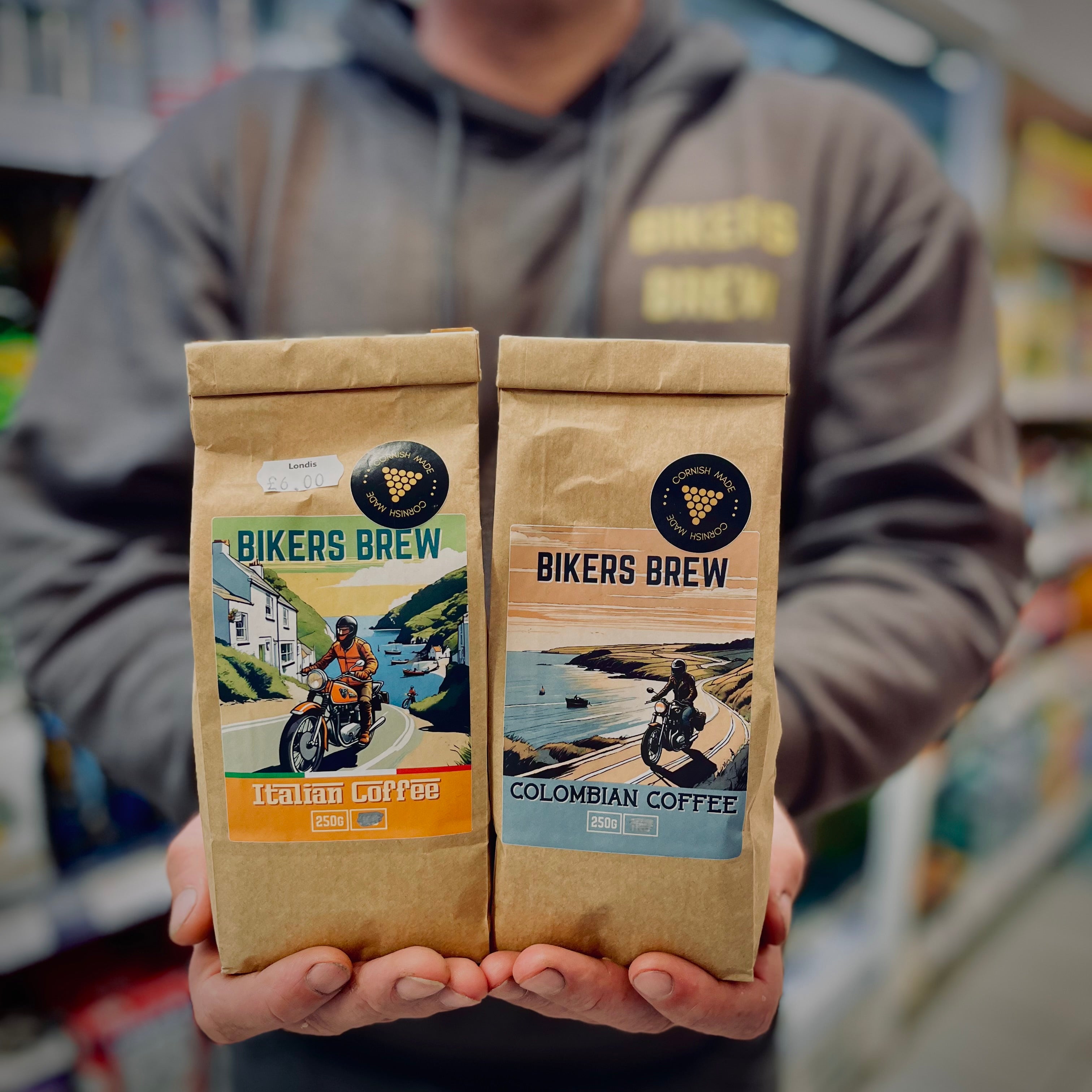 Person holding two bags of 'Bikers Brew' coffee in a store setting