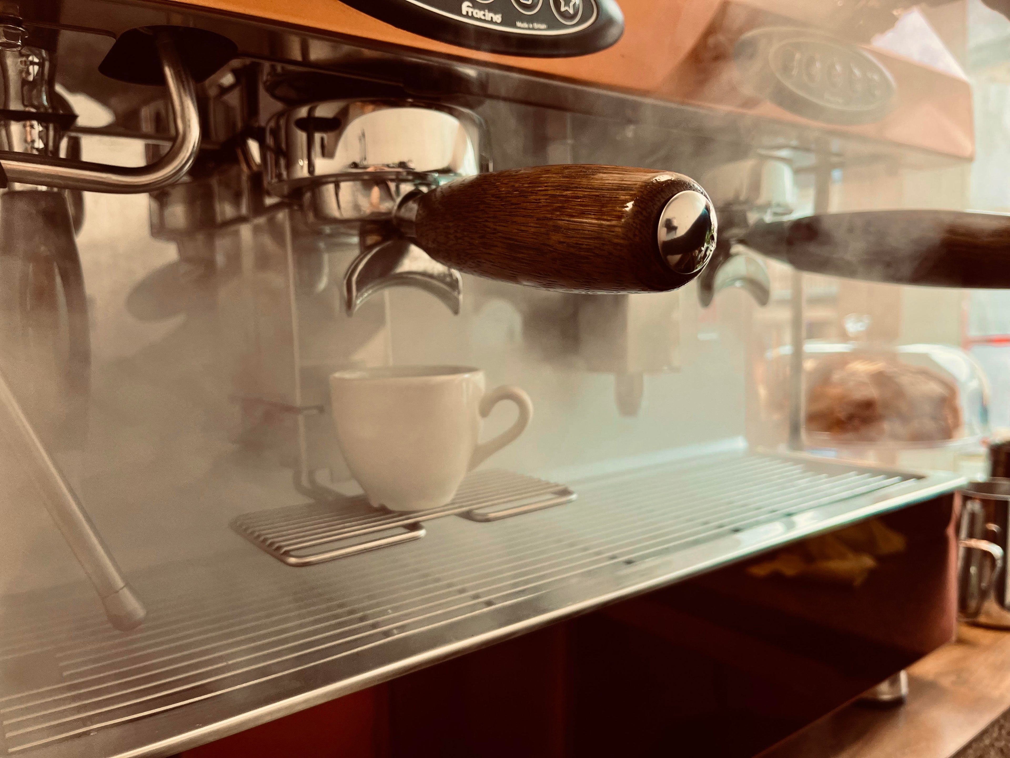Espresso machine dispensing coffee into a white cup on a wooden counter.